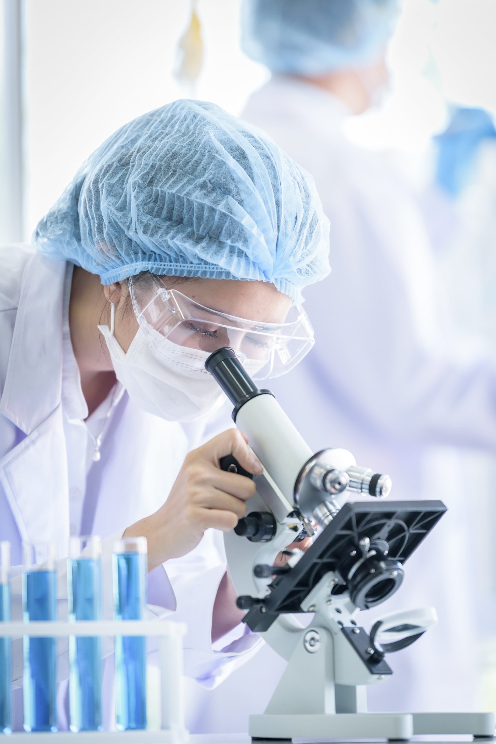 Une chercheuse qui observe un échantillon au microscope, illustrant l'engagement d'OptimHal dans la recherche pour améliorer la vie des patients.